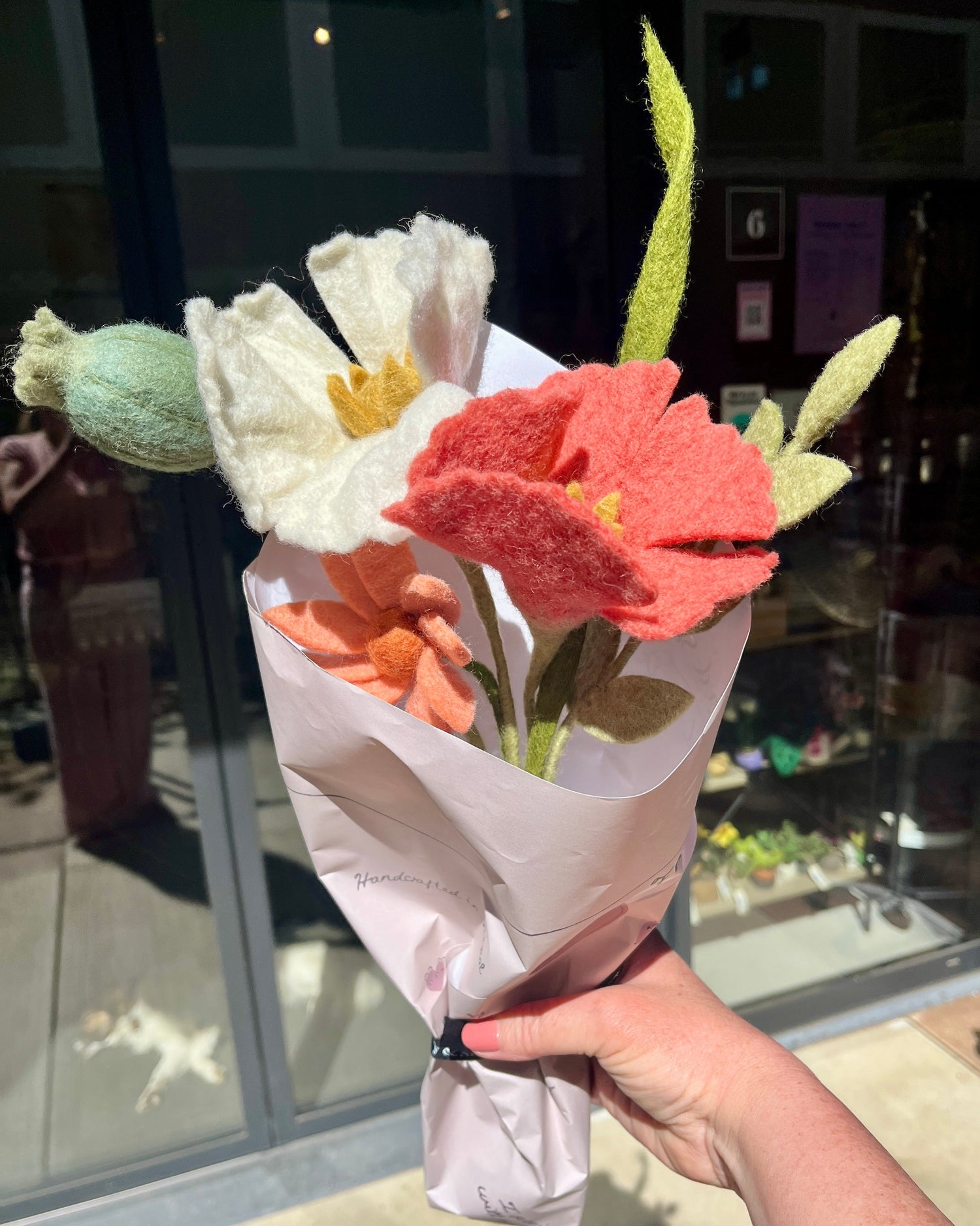 Handbeschilderd keramiek van Que Rico in wit en geel: vaas, sapkan en kleine bloempot. In de vaas staan vilten bloemen in wit en okergeel.