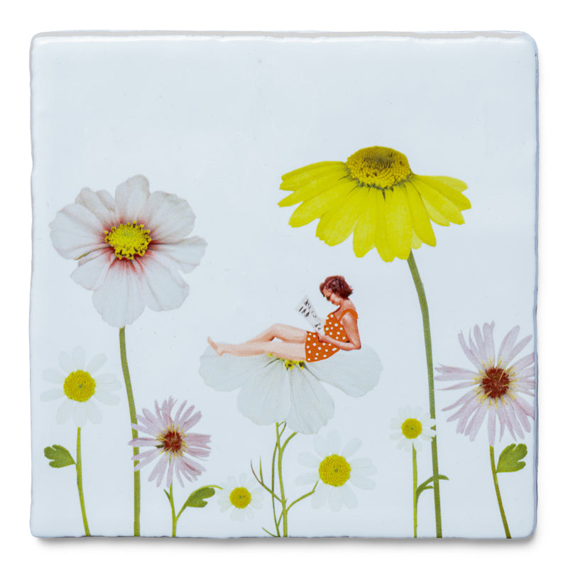 StoryTile Surrounded by flowers. Op deze decoratietegel zit een vrouw te lezen op een bloem, tussen de bloemen. ze draag een zomers oranje jurkje.