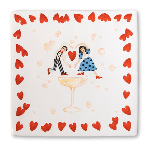 StoryTile - Proost op liefde. Deze vrolijke tegel laat een dansend stel zien op een champagneglas. Ze zijn omringd met rode hartjes. 