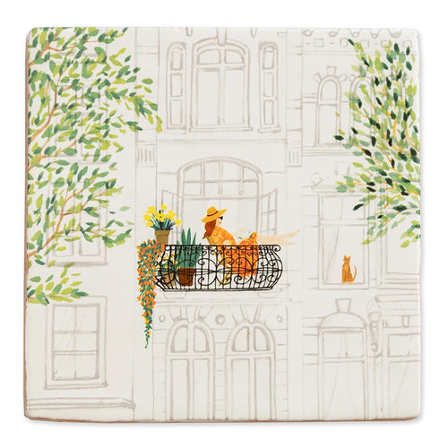 StoryTile Mijn Favoriete Plek. Op deze StoryTile staat een oud herenhuis met een Frans balkon waarop een vrouw met zomerhoed zit te relaxen tussen de planten. Voor het raam zit een rode kater. Aan beide zijden van de tegel zie je groene boomtakken.